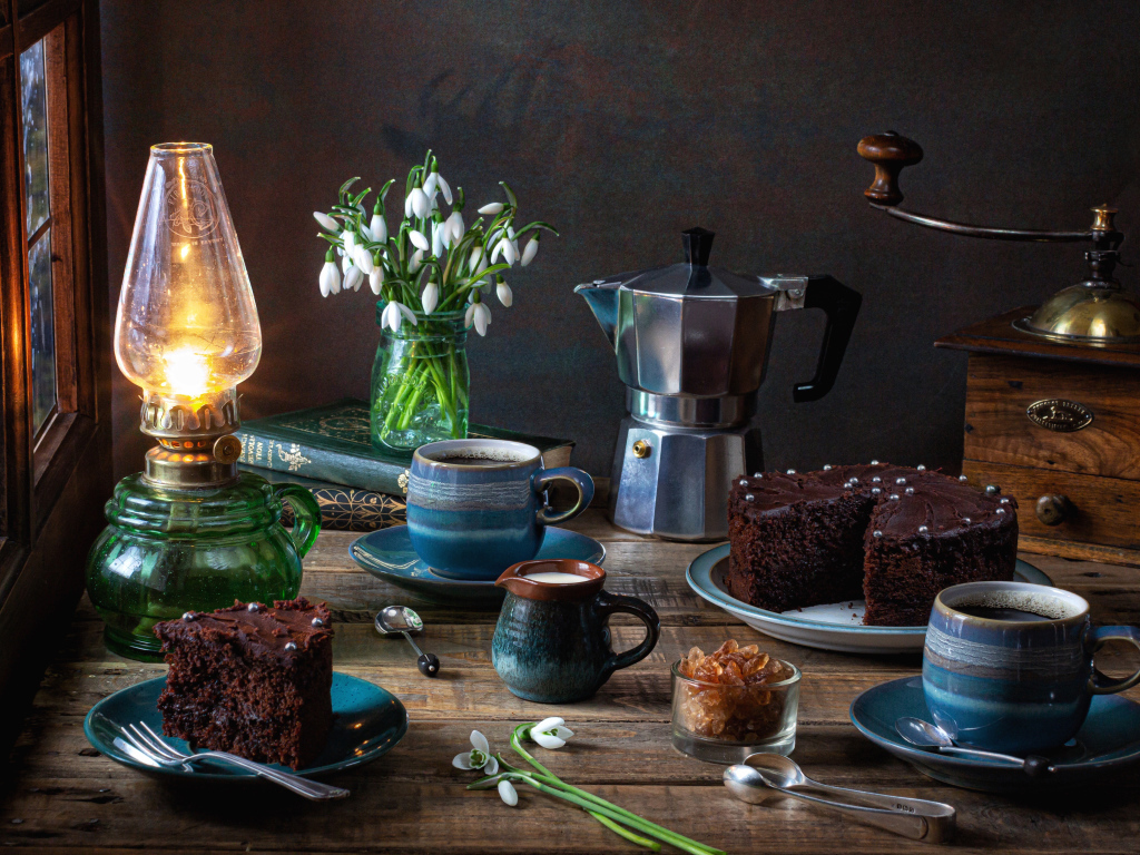 Шоколадный торт на столе с кофе, букетом подснежников и лампой
