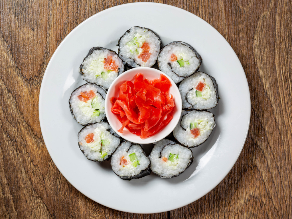 Вкусные суши на большой белой тарелке с имбирем
