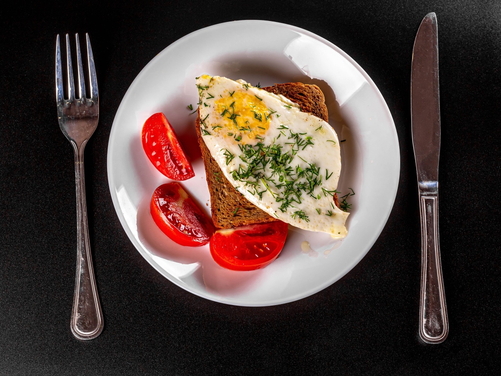 Бутерброд с яичницей на тарелке с помидорами