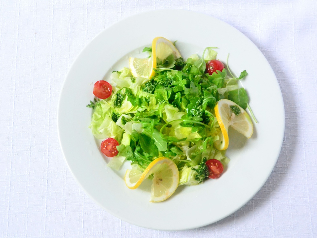 Салат из зелени с лимоном на белом фоне 