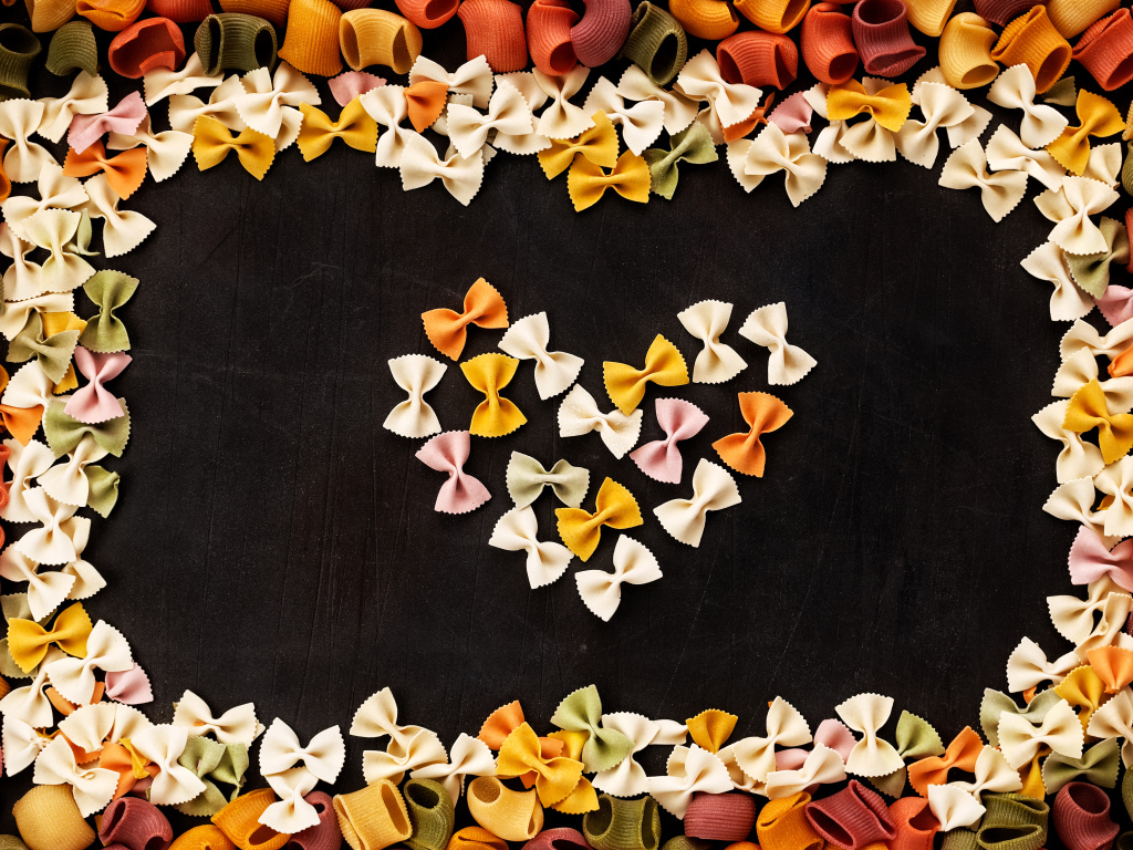 Сердце из разноцветных макарон на черном столе 