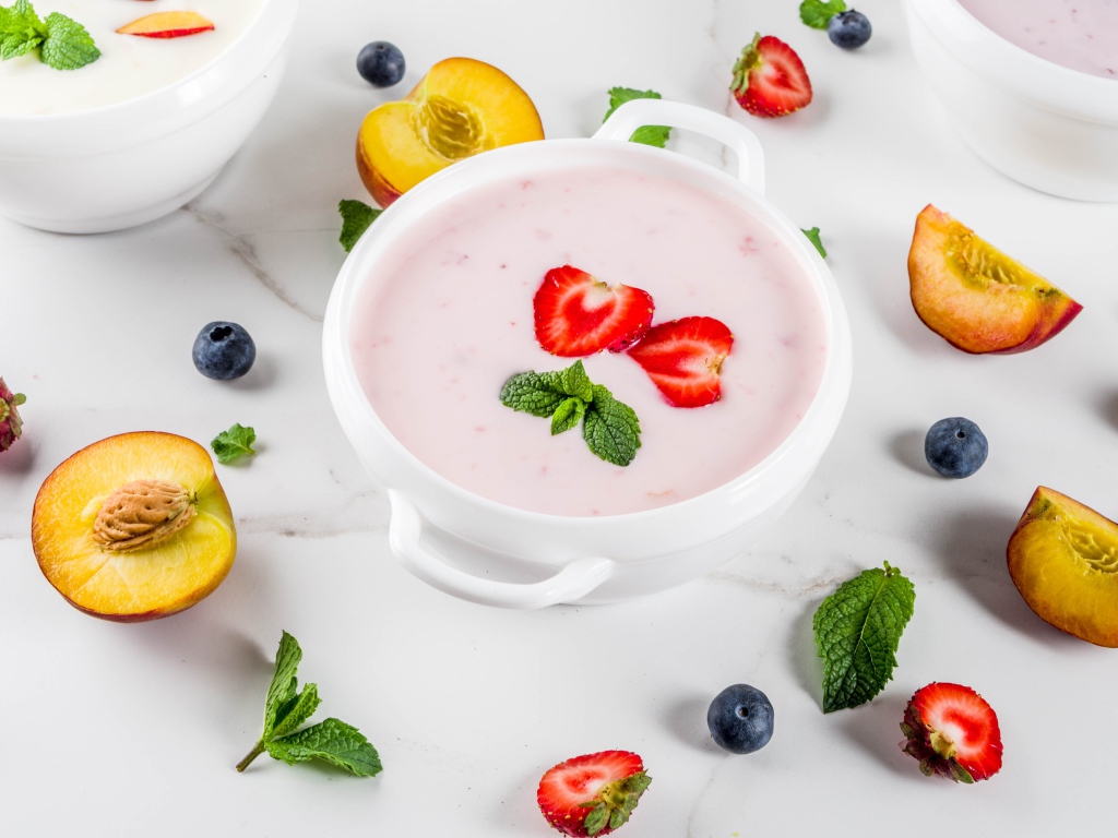 Молочный суп в тарелке на столе с ягодами и нектарином