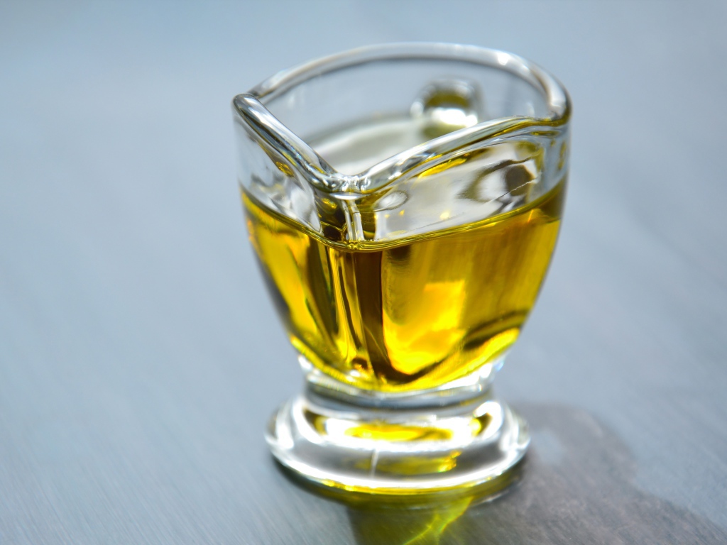 Оливковое масло в стеклянной вазе на столе 