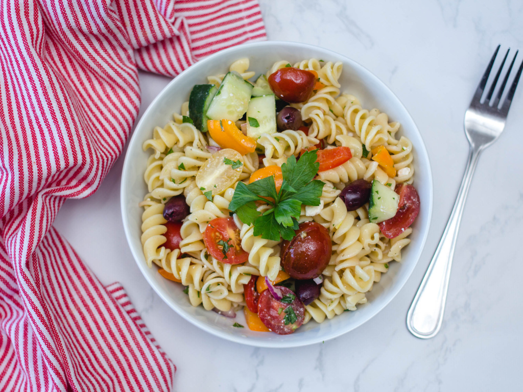 Макароны в тарелке с овощами на столе 