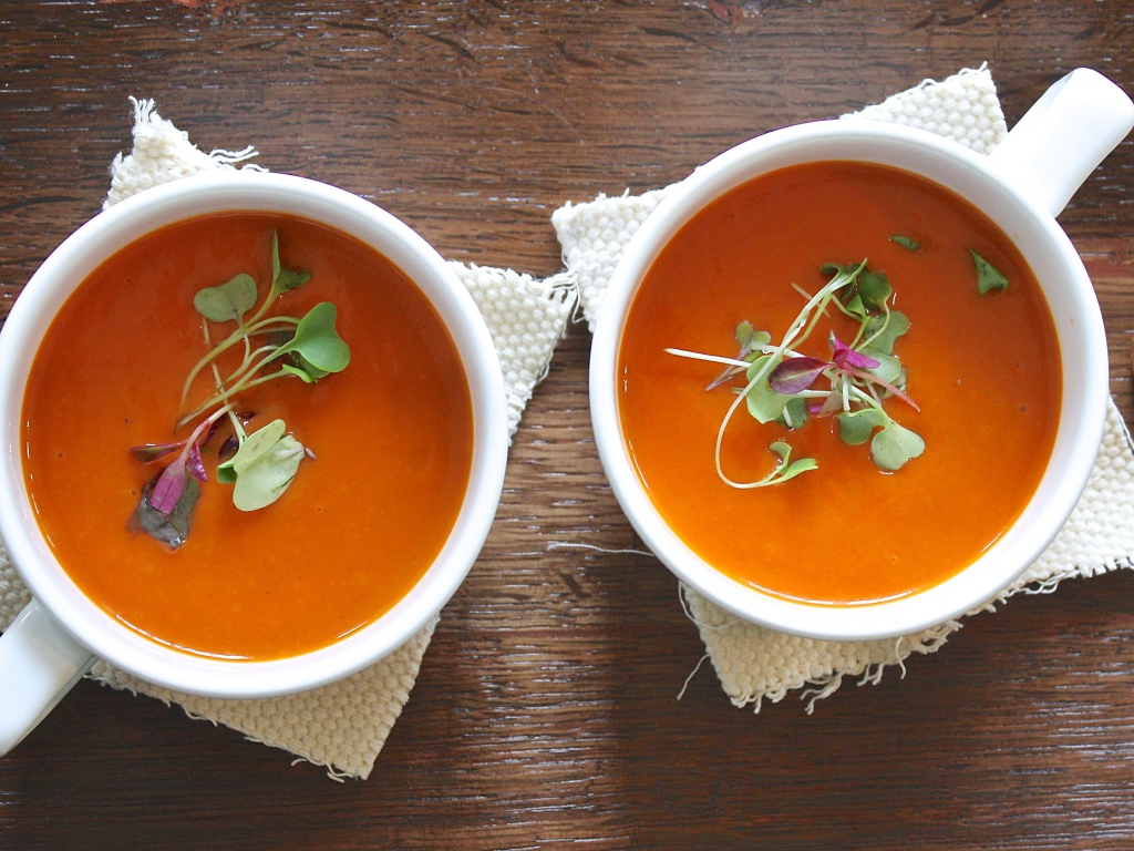 Красный суп пюре в белых чашках на столе 