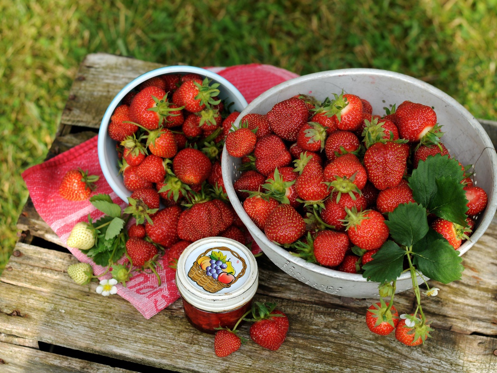Много спелой ароматной клубники на столе с джемом 