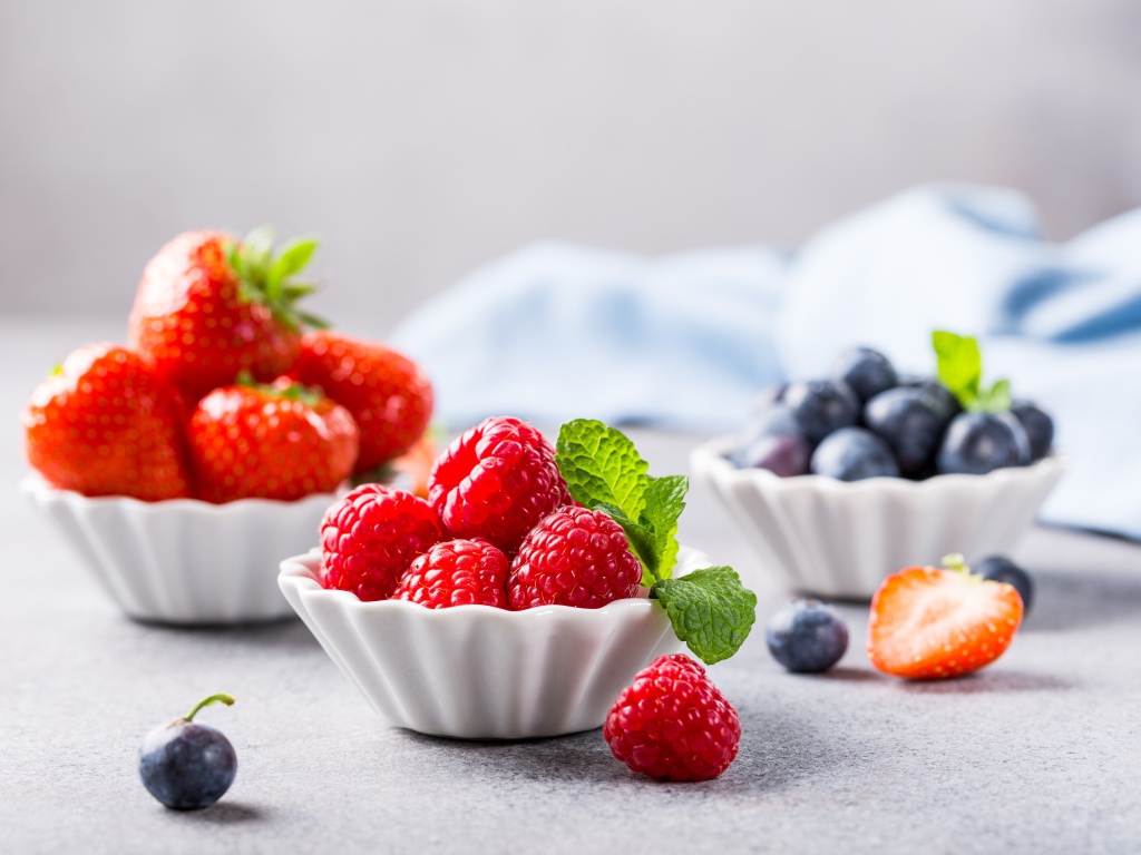 Свежие ягоды малины, клубники и черники на столе