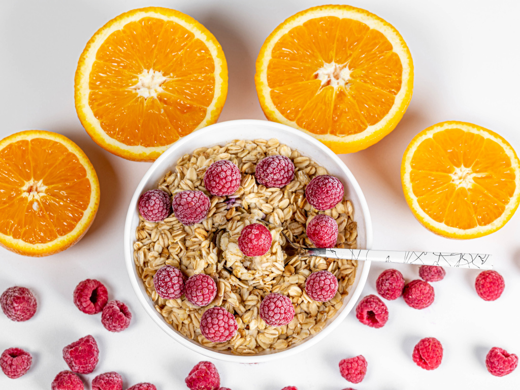 Овсяные хлопья с малиной на белом фоне с апельсинами