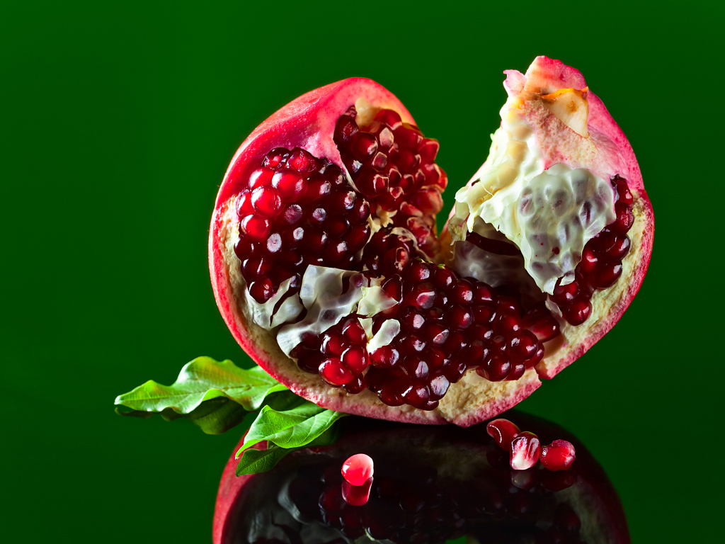 Очищенный гранат на зеленом фоне