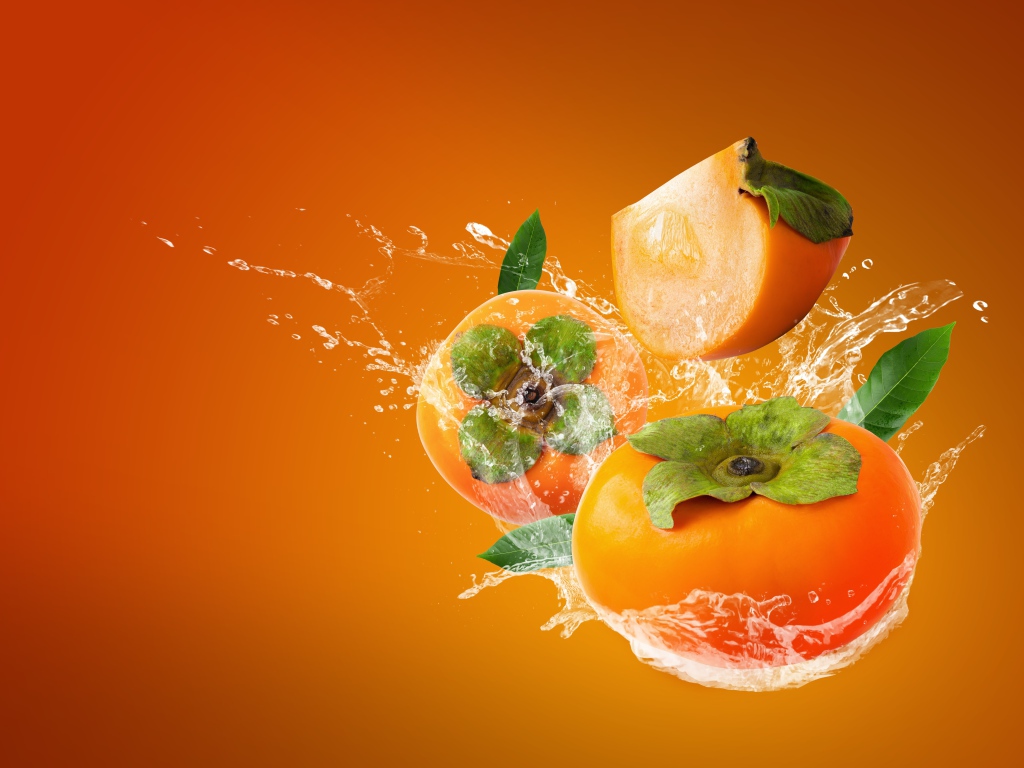 Хурма в брызгах воды на оранжевом фоне
