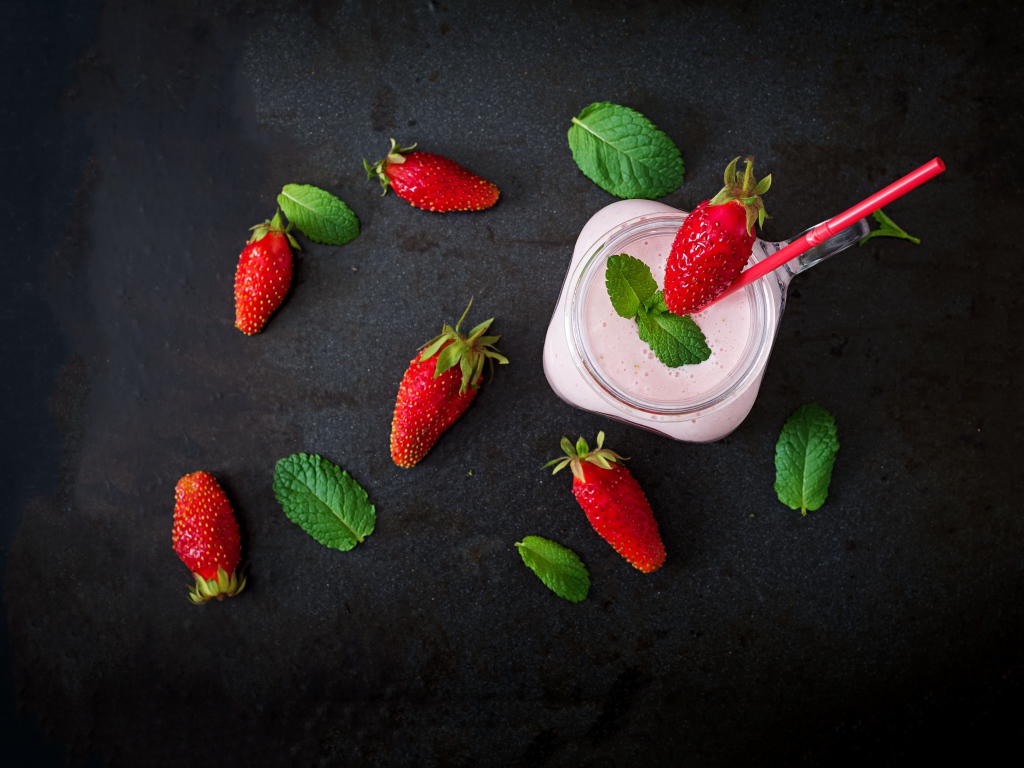 Красная клубника на черном столе с йогуртом