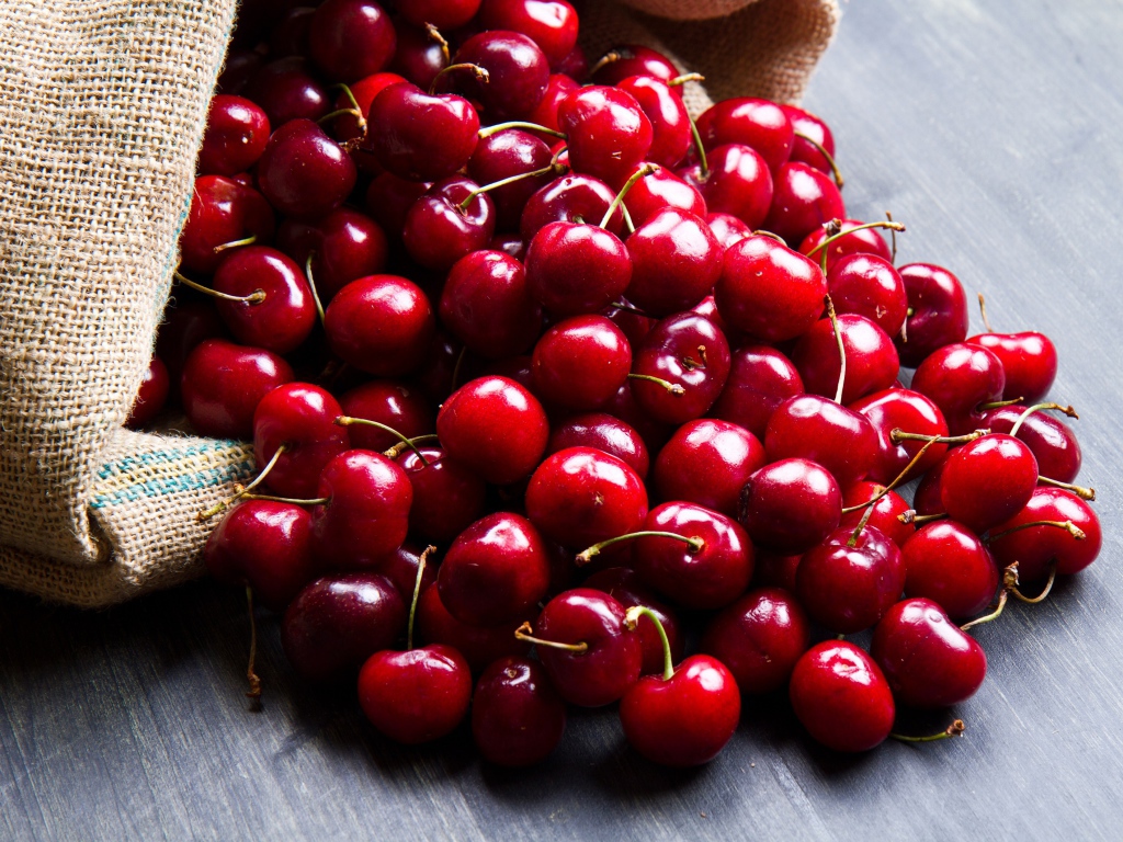 Спелые красные черешни в мешке на столе 