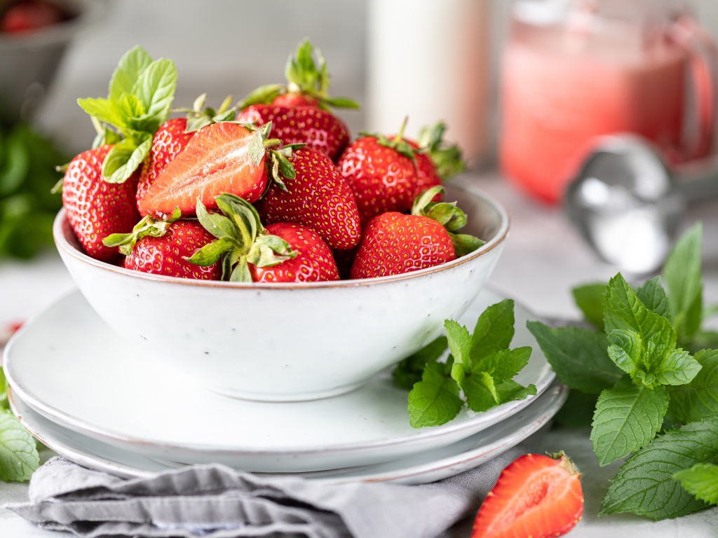 Спелая клубника с мятой на столе в белой тарелке 
