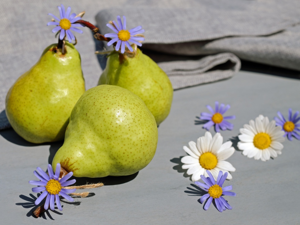 Три груши на столе с цветами
