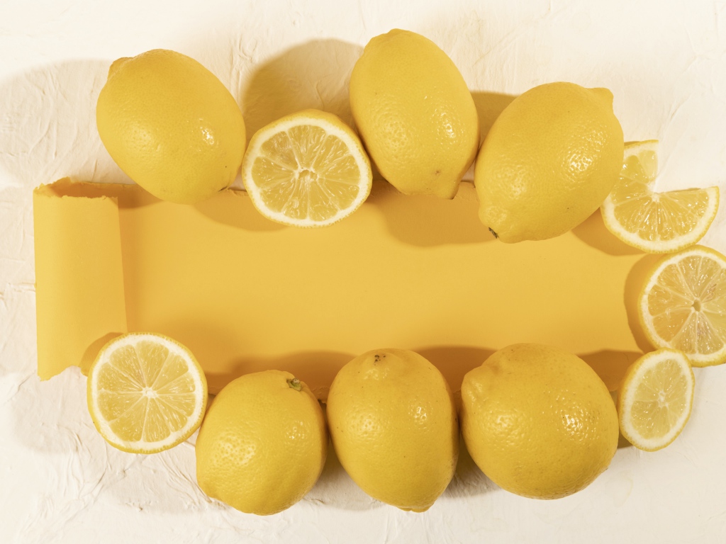 Желтые лимоны на белом фоне с листом бумаги