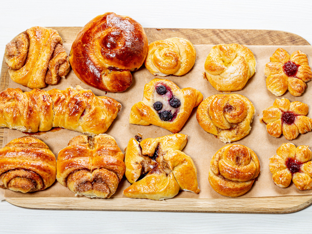 Разная свежая выпечка на доске на белом фоне