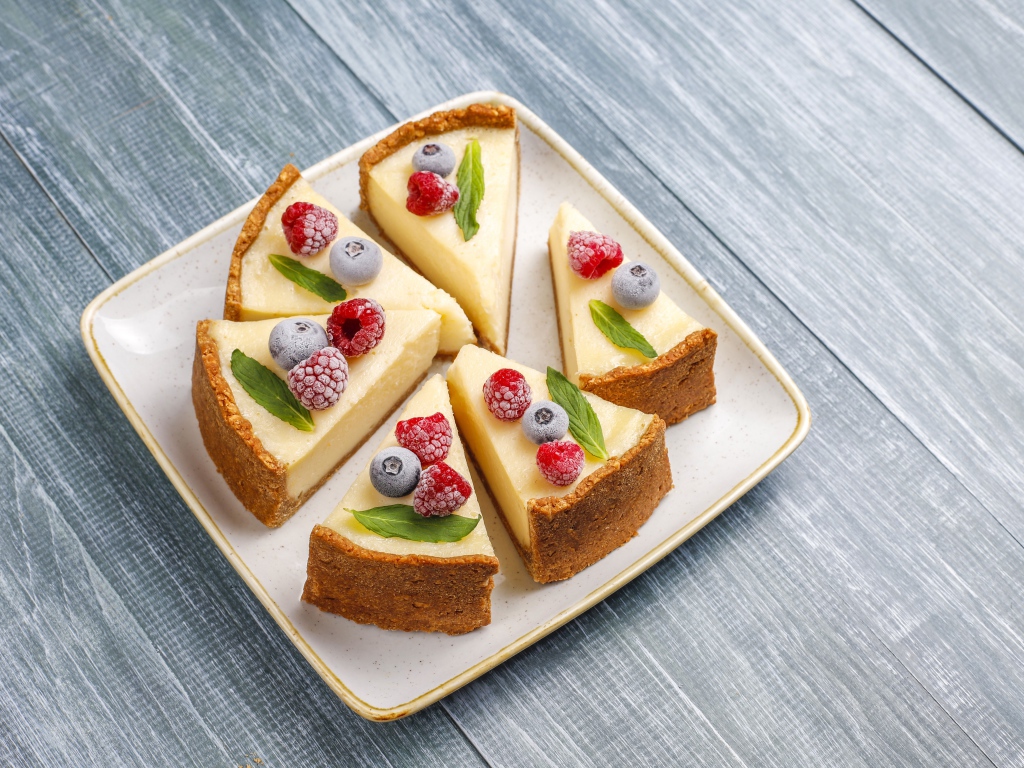 Аппетитный чизкейк с ягодами нарезан кусками на тарелке 