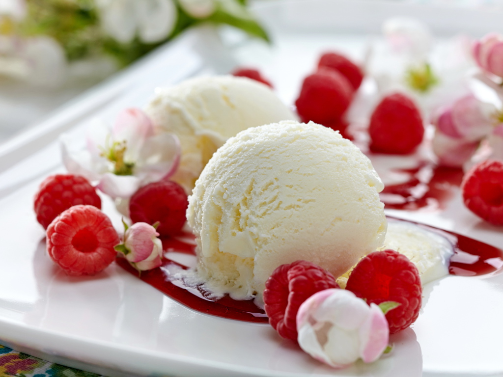 Шарики сливочного мороженого на тарелке с малиной и цветами