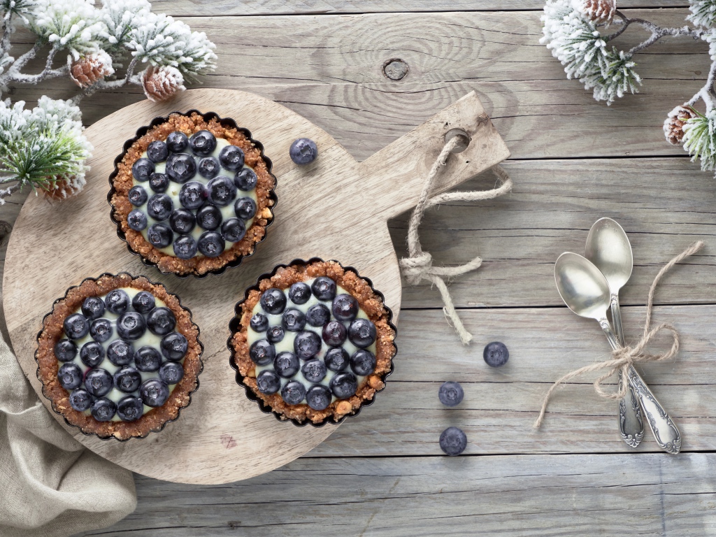 Кексы с кремом и ягодами черники на столе с чайными ложками