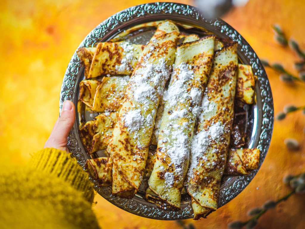 Вкусные тонкие блины с сахарной пудрой на блюде