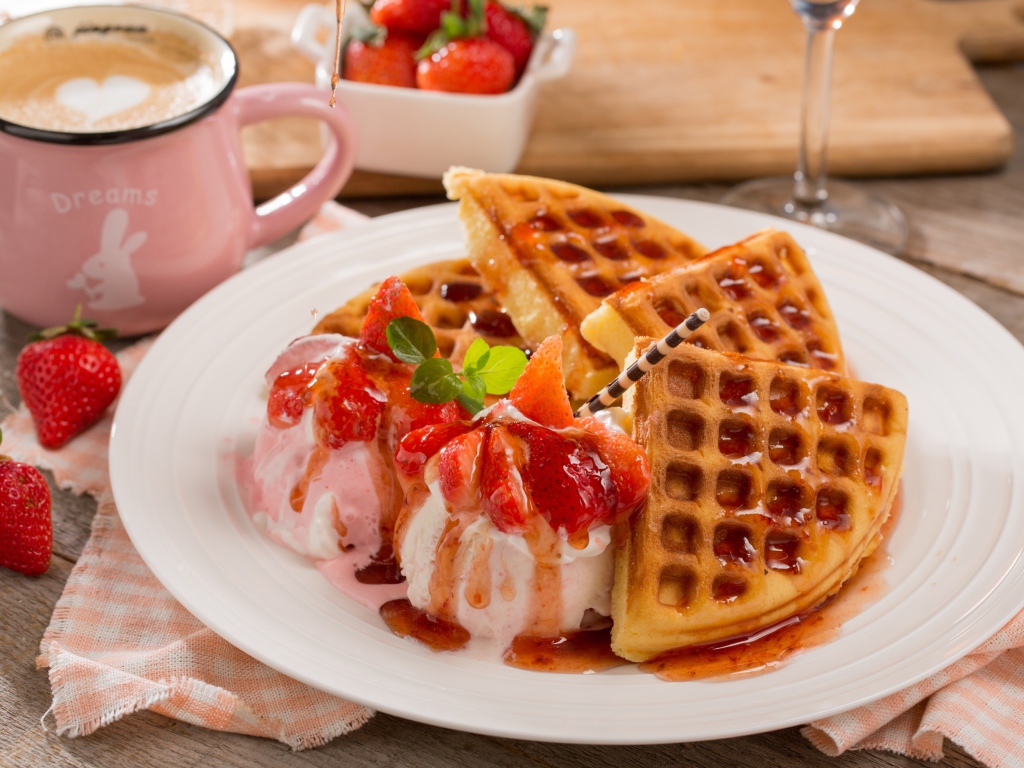 Шарики мороженого с клубникой на тарелке с вафлями и сиропом 