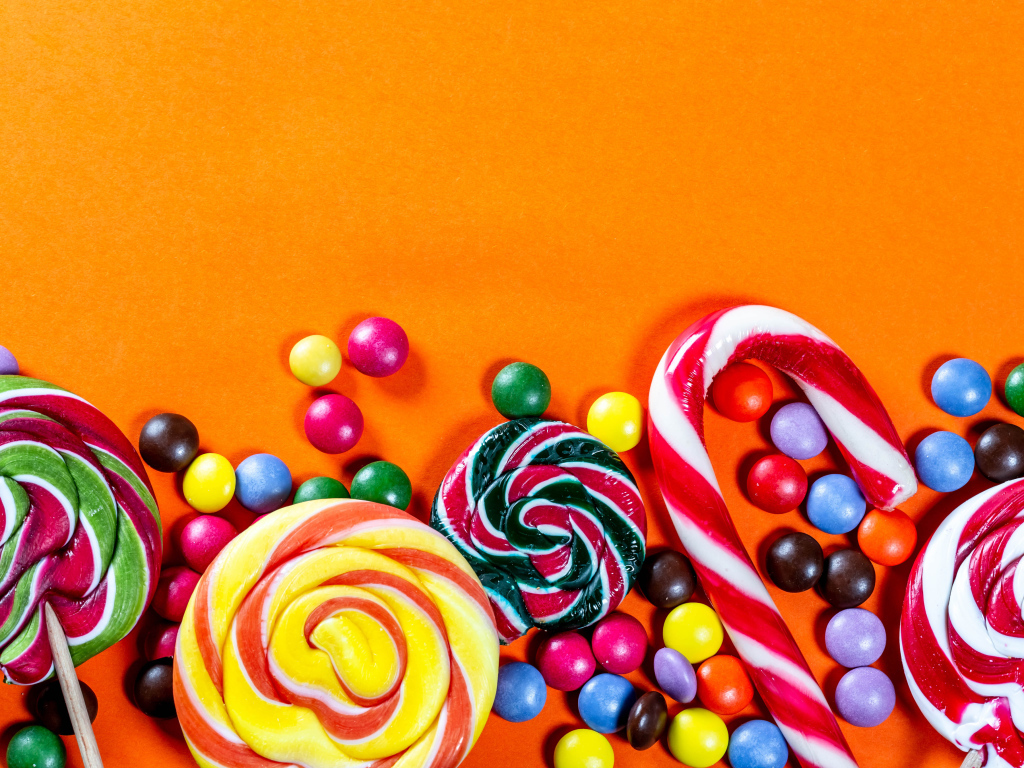 Разноцветные конфеты на оранжевом фоне