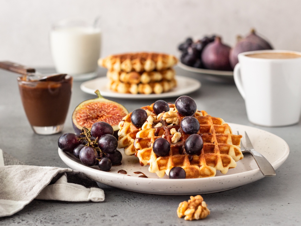 Сладкие вафли на тарелке с инжиром и виноградом