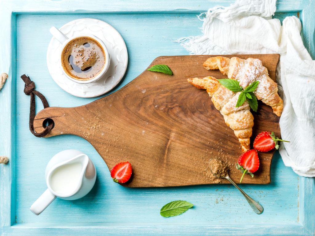 Деревянная доска на столе с круассанами и чашкой кофе