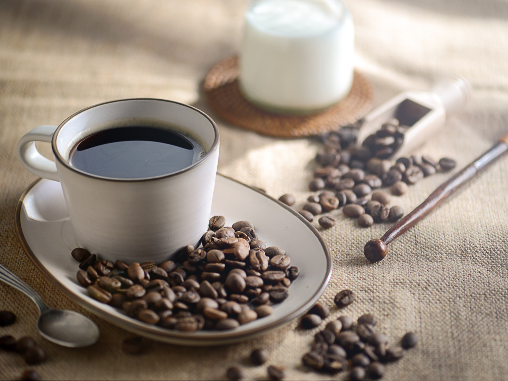 Чашка крепкого кофе на столе с зернами