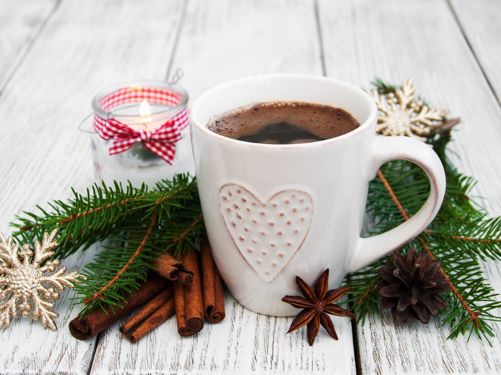 Чашка кофе на столе с еловой веткой, корицей и свечой