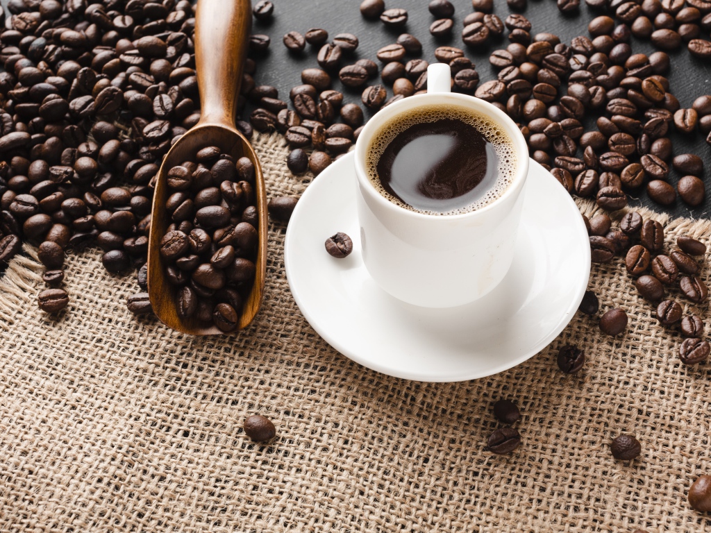 Чашка кофе на столе с зернами 