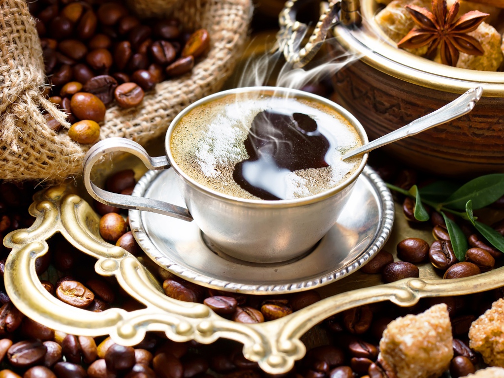 Чашка горячего вкусного кофе на столе с зернами