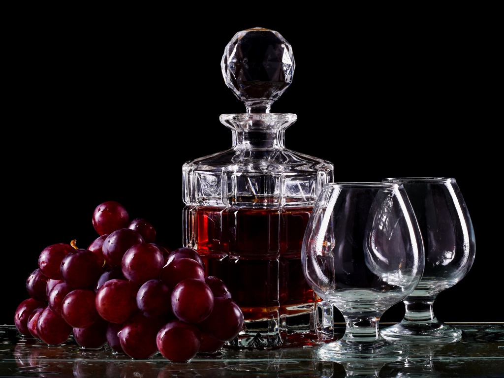 Графин с коньяком на столе с бокалами и виноградом