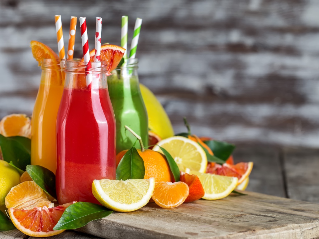 Фруктовое смузи на столе в бутылках с трубочками