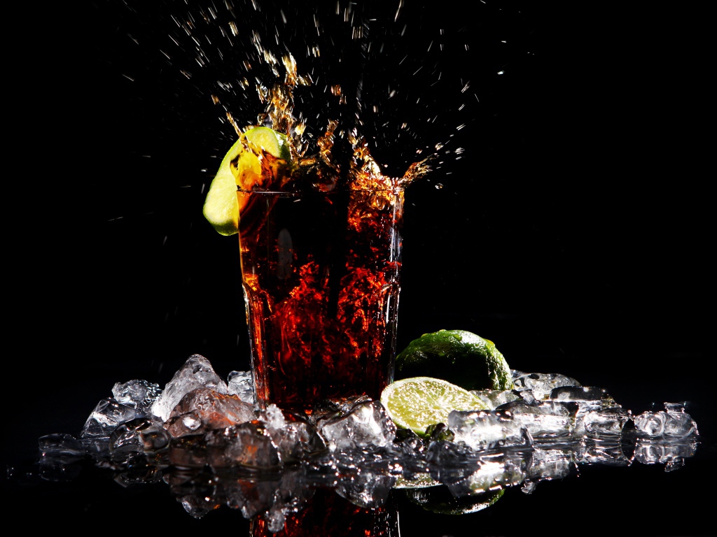 Стакан кока колы на черном фоне со льдом