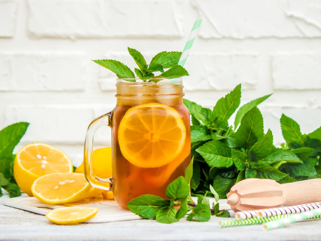 Лимонад на столе с лимоном и листьями мяты 