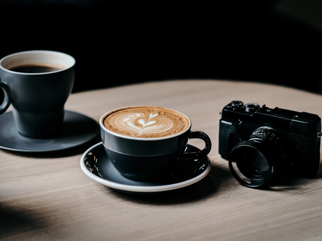 Две чашки кофе на столе с фотоаппаратом 