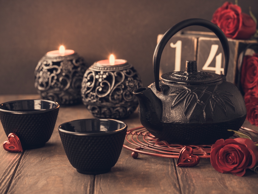 Две чашки чая на столе со свечами и красными розами