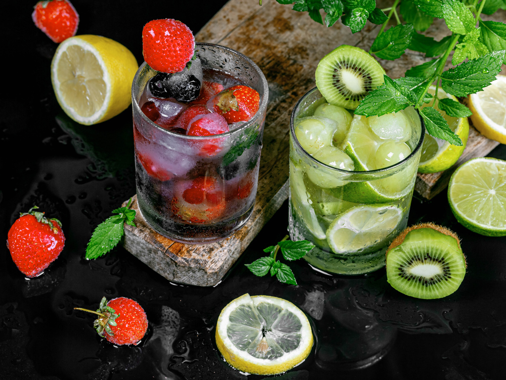 Два стакана мохито на столе с мятой, лимоном и клубникой 