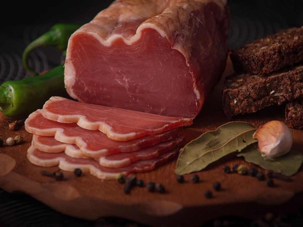 Кусок вяленого мяса на доске с черным хлебом и специями