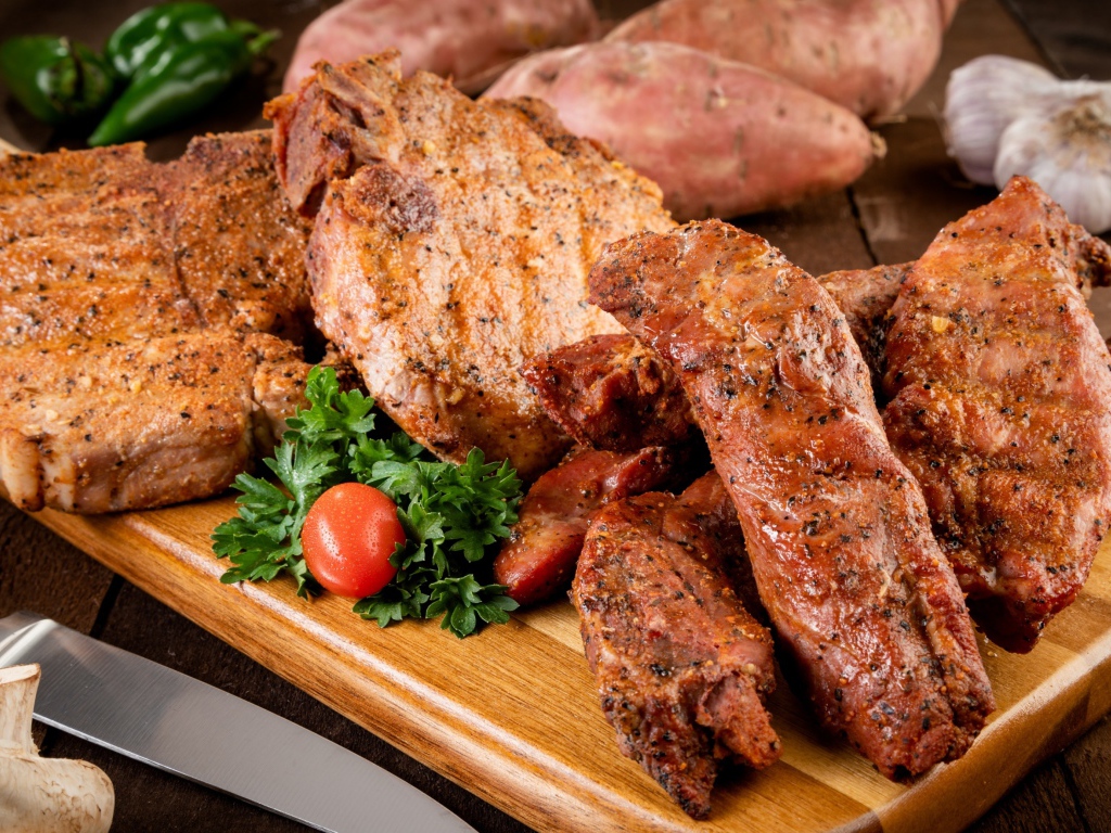 Аппетитное запеченное мясо на столе с чесноком и картофелем