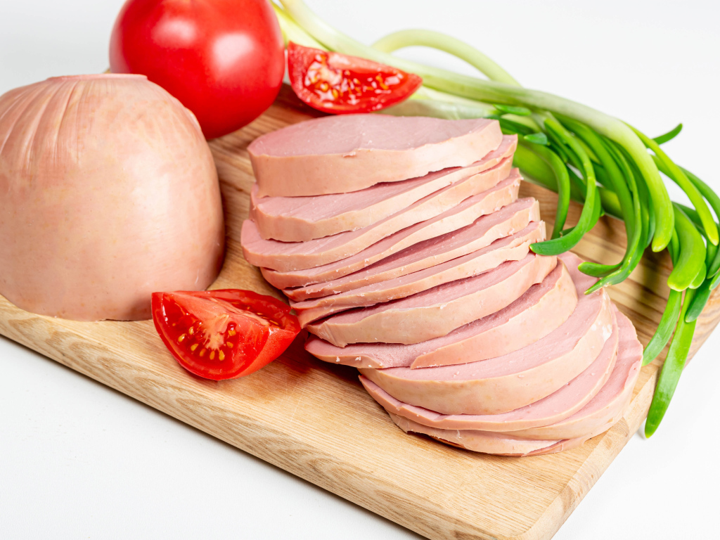 Вареная колбаса на доске с луком и помидором