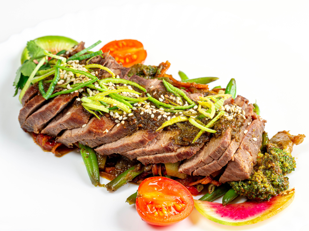 Мясо нарезанное кусочками на белом фоне с овощами