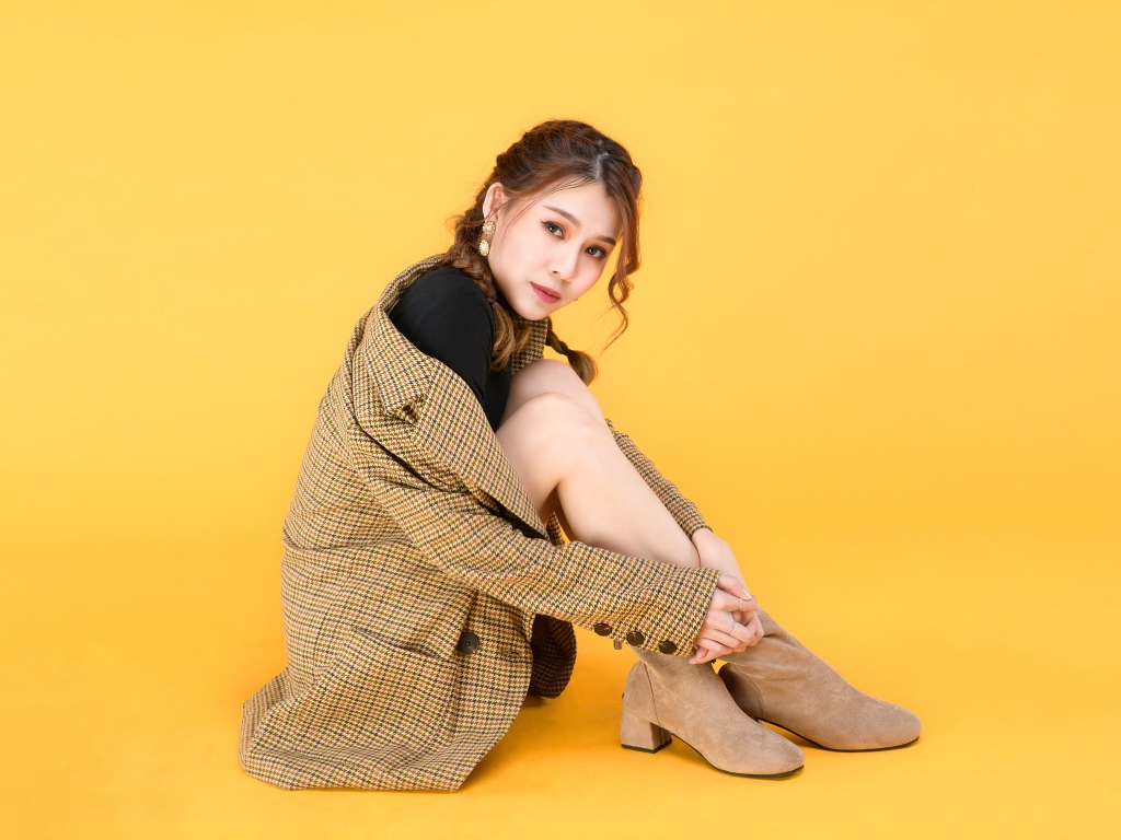 Девушка азиатка в пальто на желтом фоне 