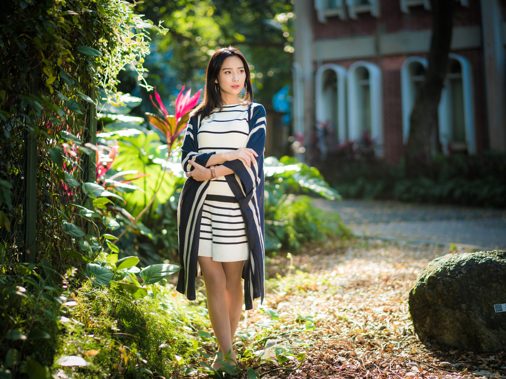 Девушка азиатка идет по улице у забора