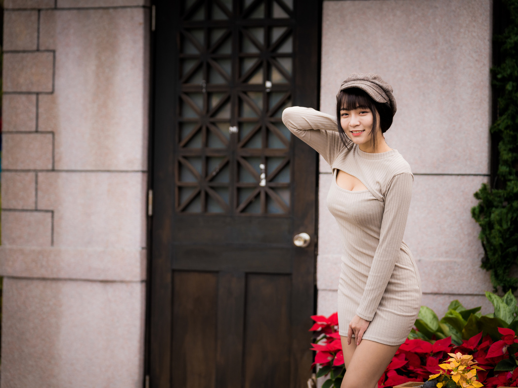 Красивая азиатка в платье стоит у двери 