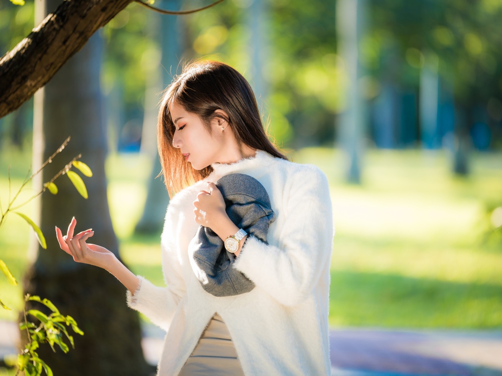 Красивая азиатка в белой кофте в солнечном парке