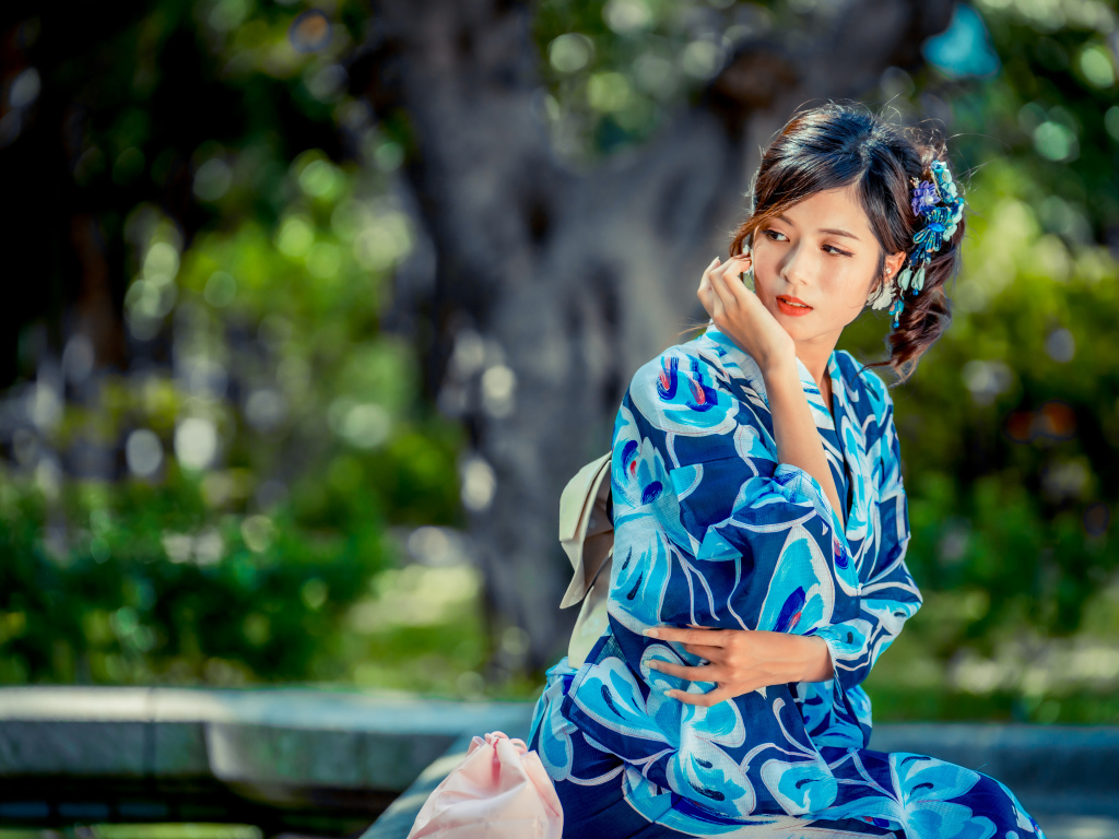 Красивая азиатка в разноцветном кимоно в парке