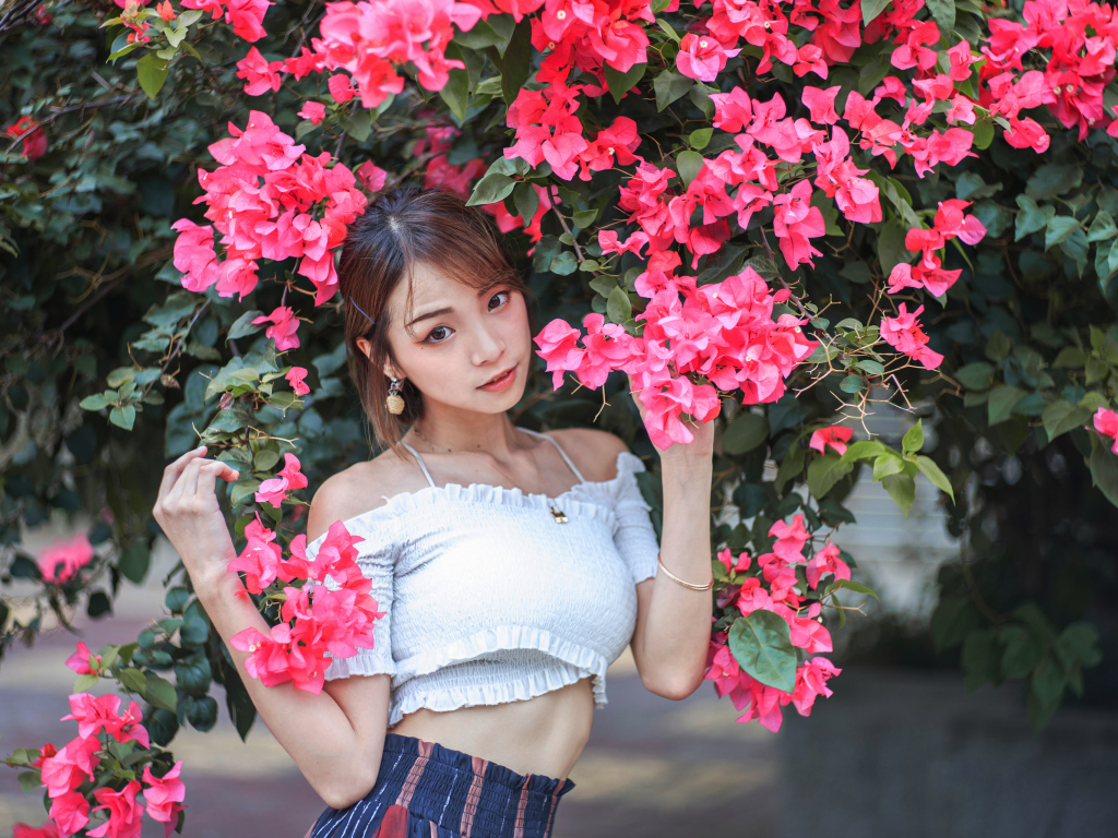 Красивая азиатка стоит у дерева с красными цветами