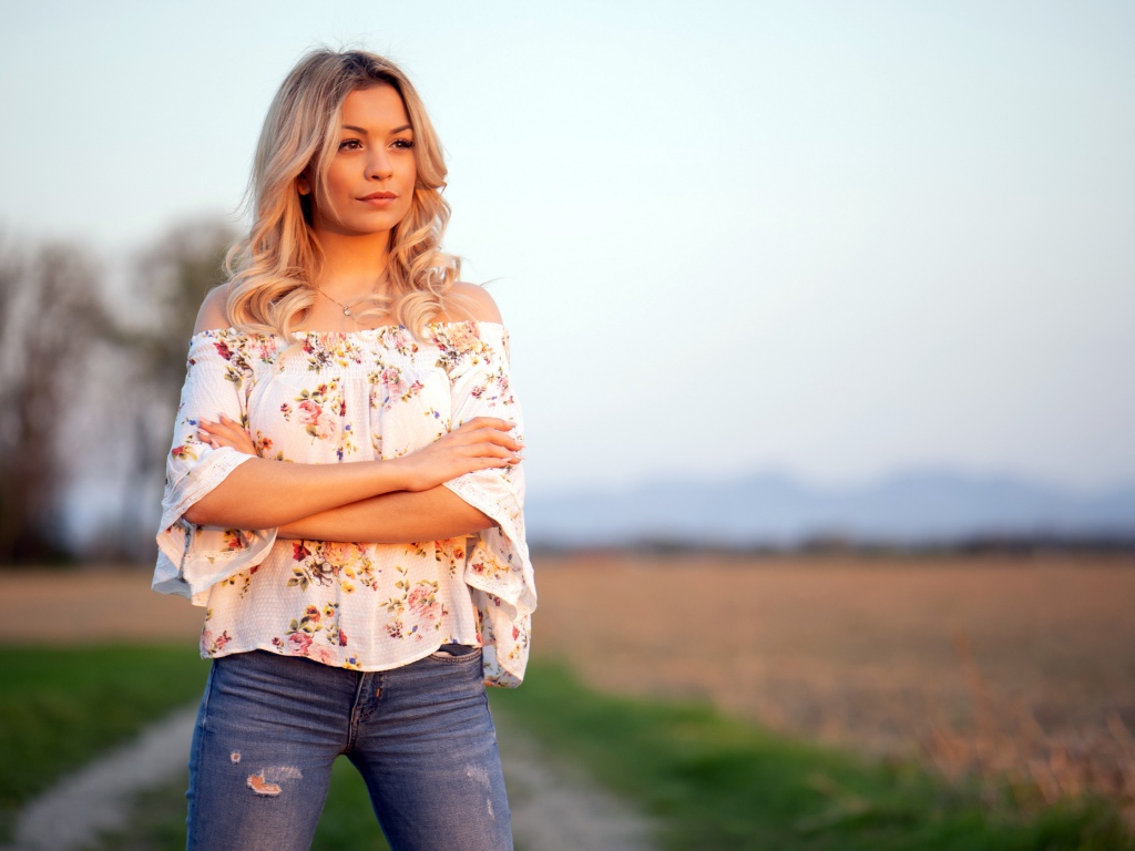 Красивая девушка блондинка в джинсах в поле